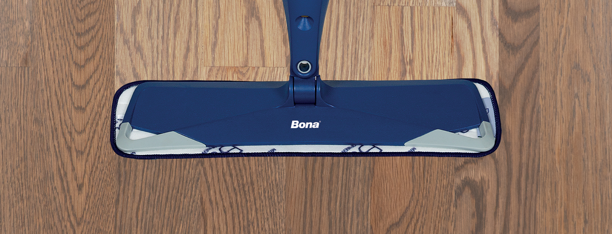 A Bona Spray Mop cleans a hardwood floor. There is a noticeable difference between the cleaned and uncleaned floor sections.